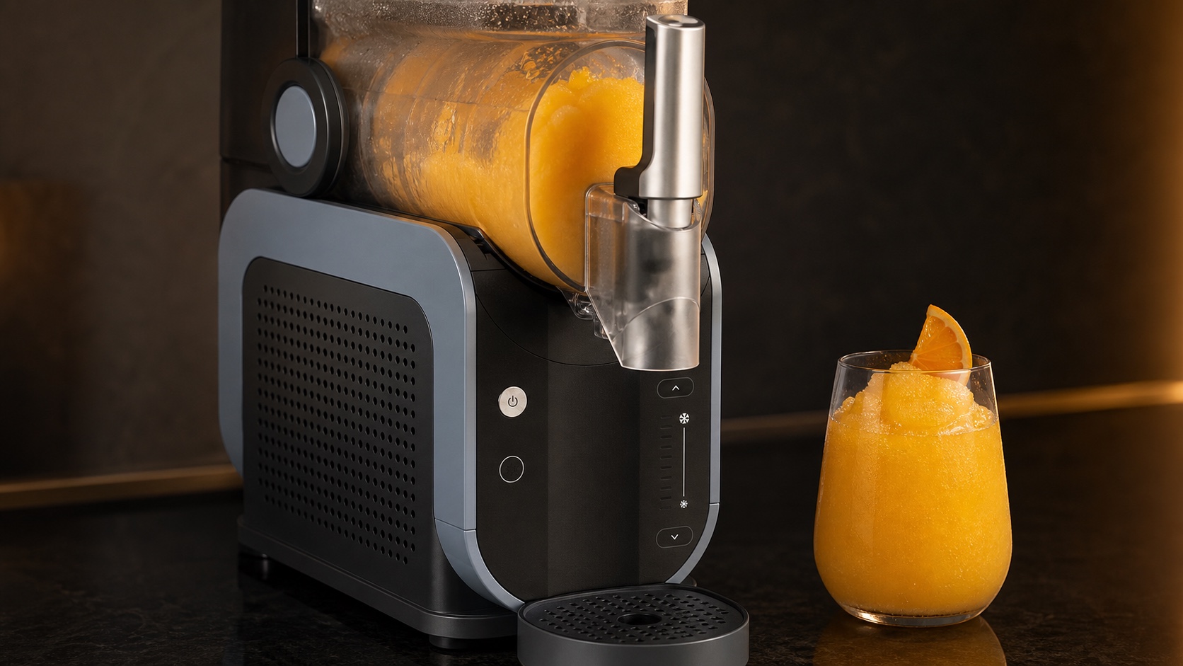 Close detail of a Ninja SLUSHi FS301-style machine with mango-orange slush in its horizontal chamber and a finished glass beside the spout.